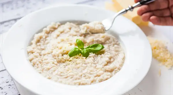 Kremowe risotto bianco z parmezanem i bazylią, gotowe do zjedzenia.