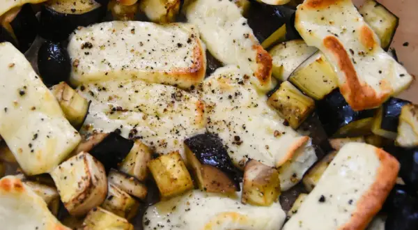 Pyszne halloumi z piekarnika, zapieczone z kawałkami bakłażana, posypane świeżo mielonym pieprzem. Idealne danie.