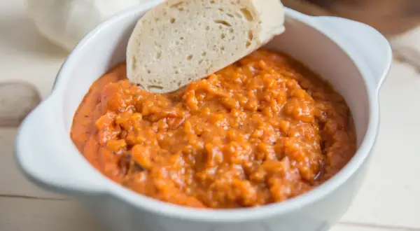 Gęsta, aromatyczna toskańska zupa pomidorowa z kawałkiem chleba, podana w białej miseczce.