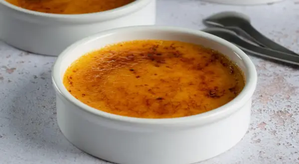 Dwa białe naczynia z pyszną, skarmelizowaną górą, idealne na deser crema catalana.