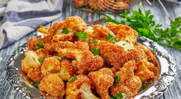 Chrupiące warzywa w panko, podane na ozdobnej tacy, posypane natką pietruszki. Idealna przekąska!