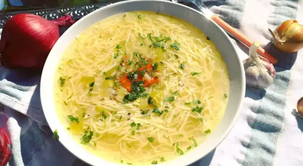Aromaticzny, złocisty, dobry rosół z makaronem i natką pietruszki, obok cebula i czosnek.