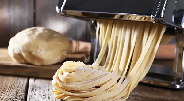 Maszyna do makaronu tworzy świeże tagliatelle z ciasta. Idealny sposób, jak zrobić makaron w domu.