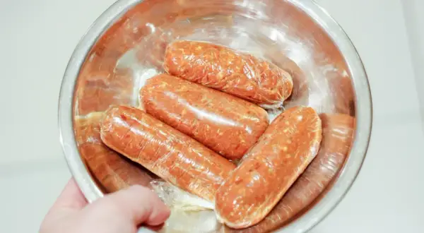 Cztery surowe kiełbaski chorizo w folii spożywczej, gotowe do przygotowania pysznego dania.