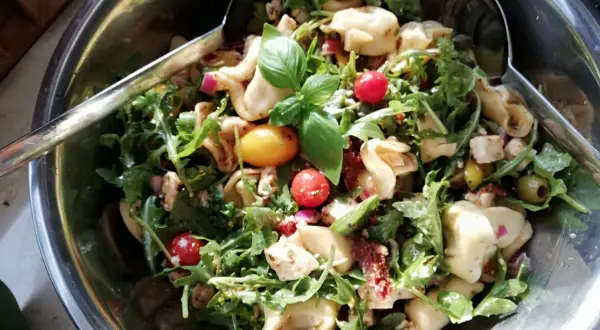 Pyszna sałatka tortellini z rukolą, pomidorkami koktajlowymi, oliwkami i serem feta. Idealna na letnie przyjęcie.