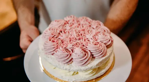 Dwupoziomowy tort lodowo bezowy z różową dekoracją z kremu. Idealny na letnie przyjęcie, oto przepis!