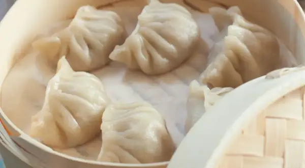 Pyszne pierożki na parze w bambusowym parowniku, gotowe do podania.