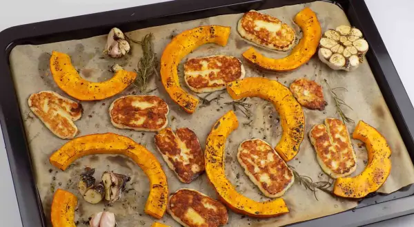 Pieczona dynia piżmowa z serem halloumi i czosnkiem na blasze.