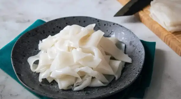 Płaski, biały makaron ryżowy na talerzu, gotowy do przygotowania pysznych dań. Szukasz inspiracji? Sprawdź makaron vermicelli przepisy!