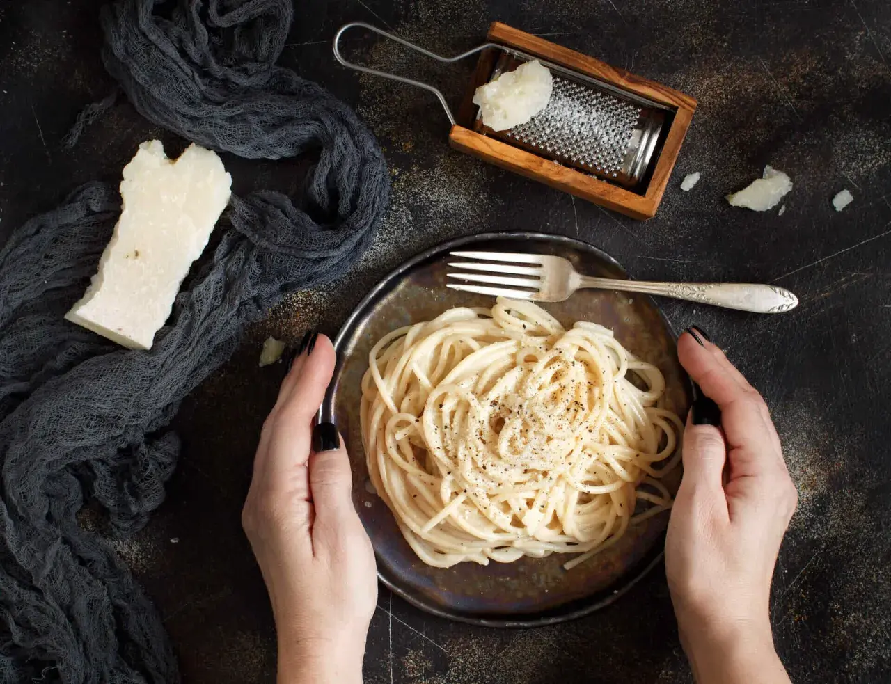 Idealny ser do spaghetti? Ten parmezan starty na tarce i kawałek obok talerza z makaronem sugerują odpowiedź.