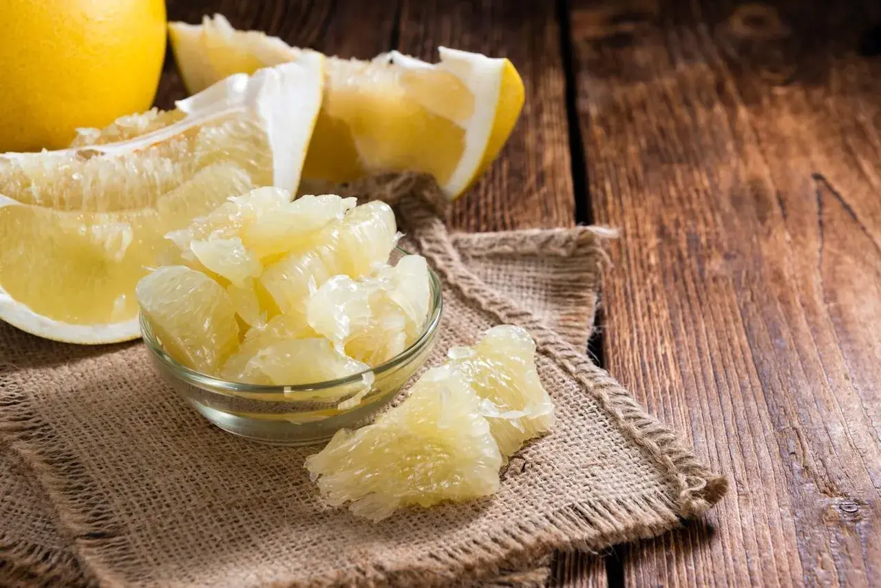 Soczyste kawałki pomelo w miseczce i obok, pokazujące, jak jeść ten owoc.