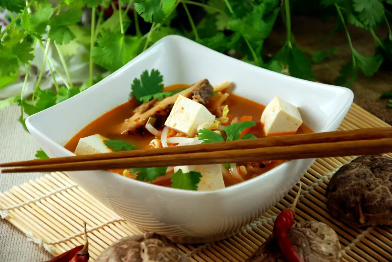 Aksamitna zupa koreańska z kostkami tofu, kiełkami i świeżą kolendrą, gotowa do spożycia pałeczkami.