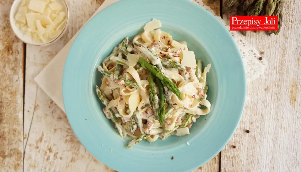 Tagliatelle ze szparagami w kremowym sosie, posypane parmezanem. Pyszne danie na wiosnę.