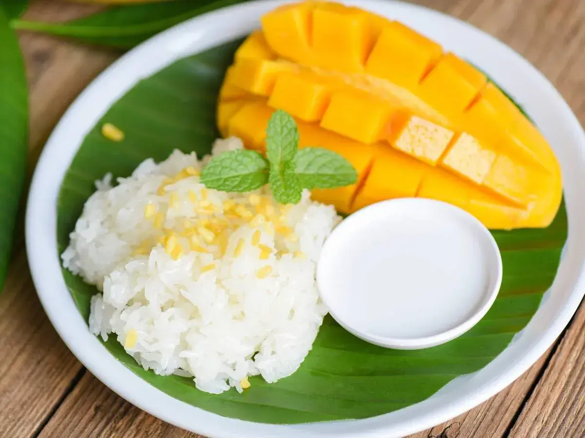 Pyszny mango sticky rice: soczyste mango, kleisty ryż, mleczko kokosowe i listek mięty na liściu bananowca.