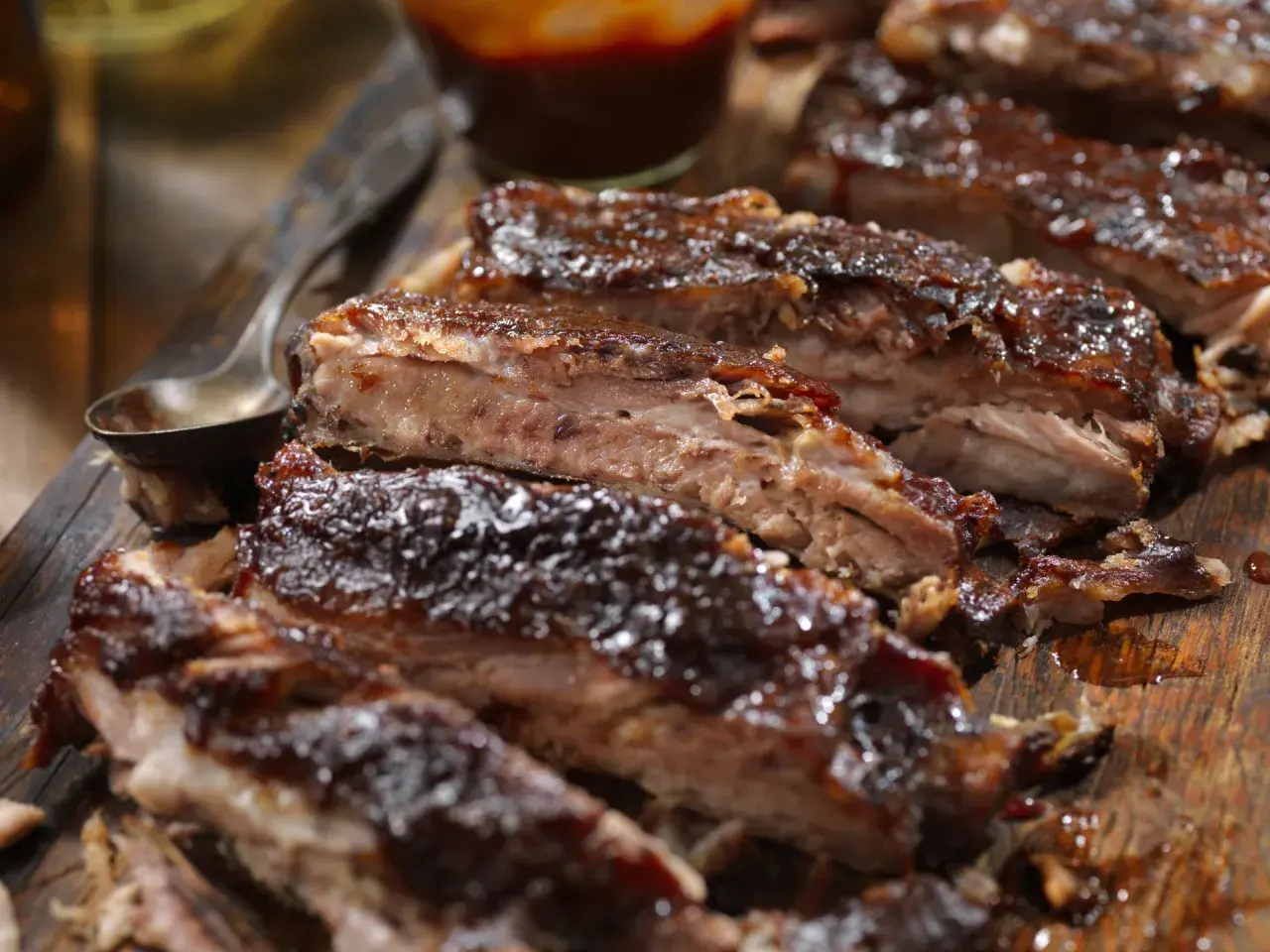 Soczyste żeberka w piwie, polane gęstym sosem BBQ, prezentują się apetycznie na drewnianej desce.
