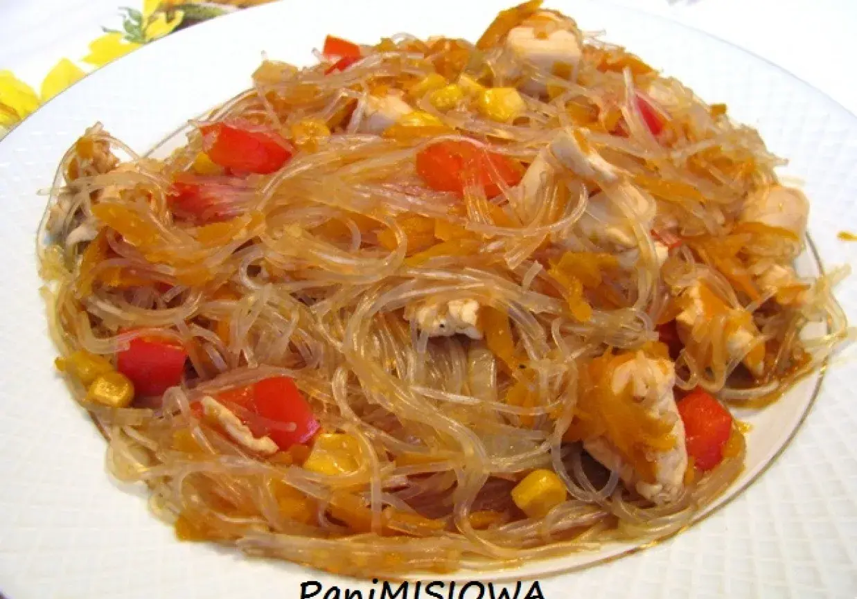 Pyszny kurczak z makaronem sojowym, papryką i kukurydzą na białym talerzu.