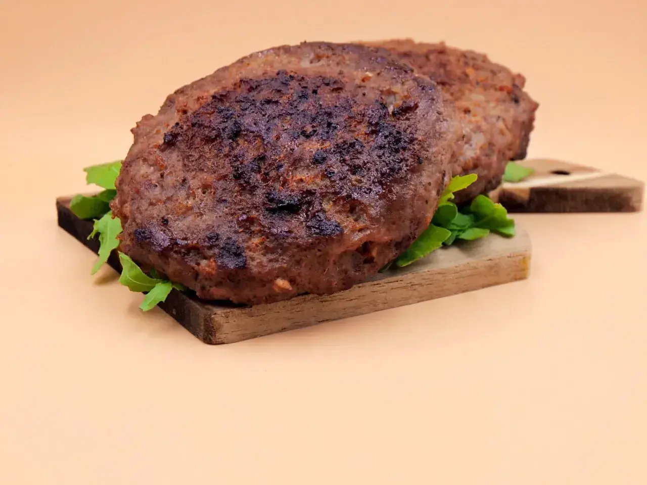 Dwa soczyste kotlety na desce, idealne do burgera. Dowiedz się, jak smażyć burgera, by były tak pyszne!