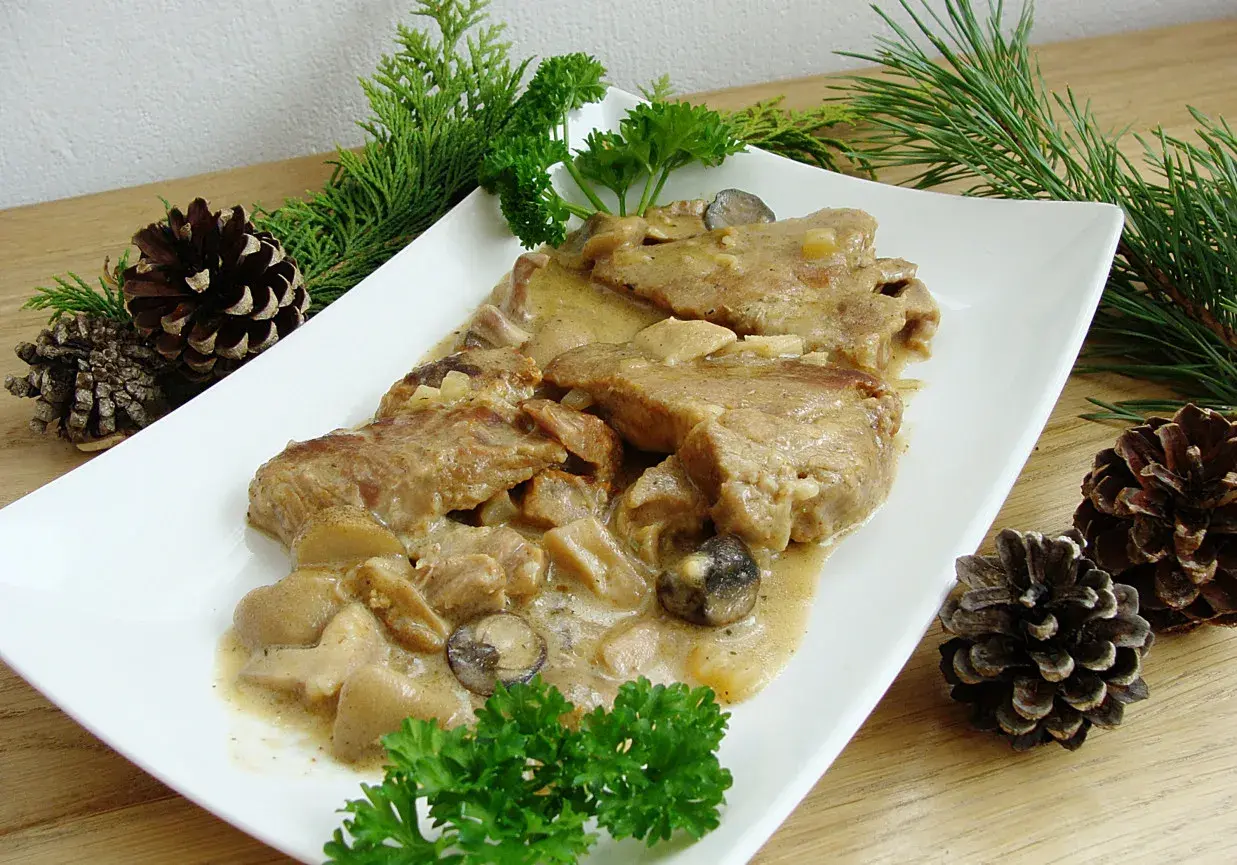 Karkówka w sosie grzybowym, podana z gałązkami iglaków i szyszkami, wygląda apetycznie.