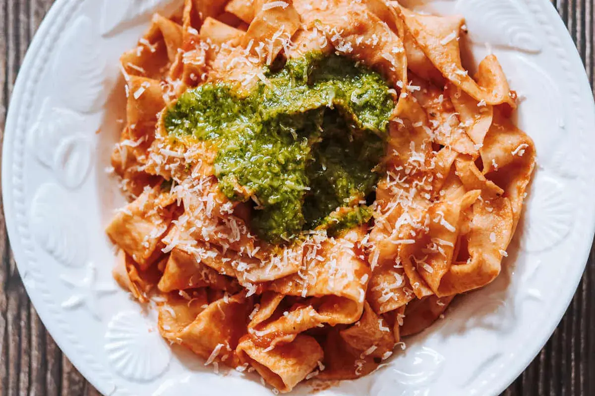 Pappardelle all'arrabbiata przepis: szeroki makaron z pikantnym sosem pomidorowym, zielonym pesto i parmezanem.