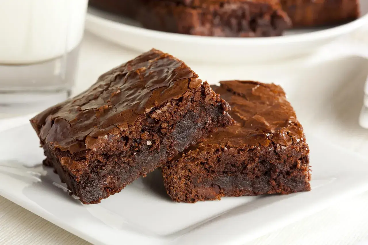 Dwa wilgotne brownie z nutellą, posypane solą morską, na białym talerzyku.