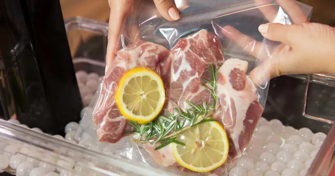Mięso wieprzowe z cytryną i rozmarynem w woreczku do metody sous vide, gotowe do kąpieli wodnej.