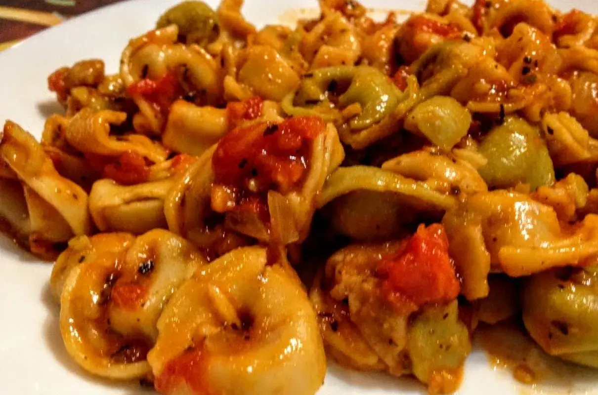 Pyszne tortellini z pomidorami i mozzarellą w sosie, danie gotowe do podania.