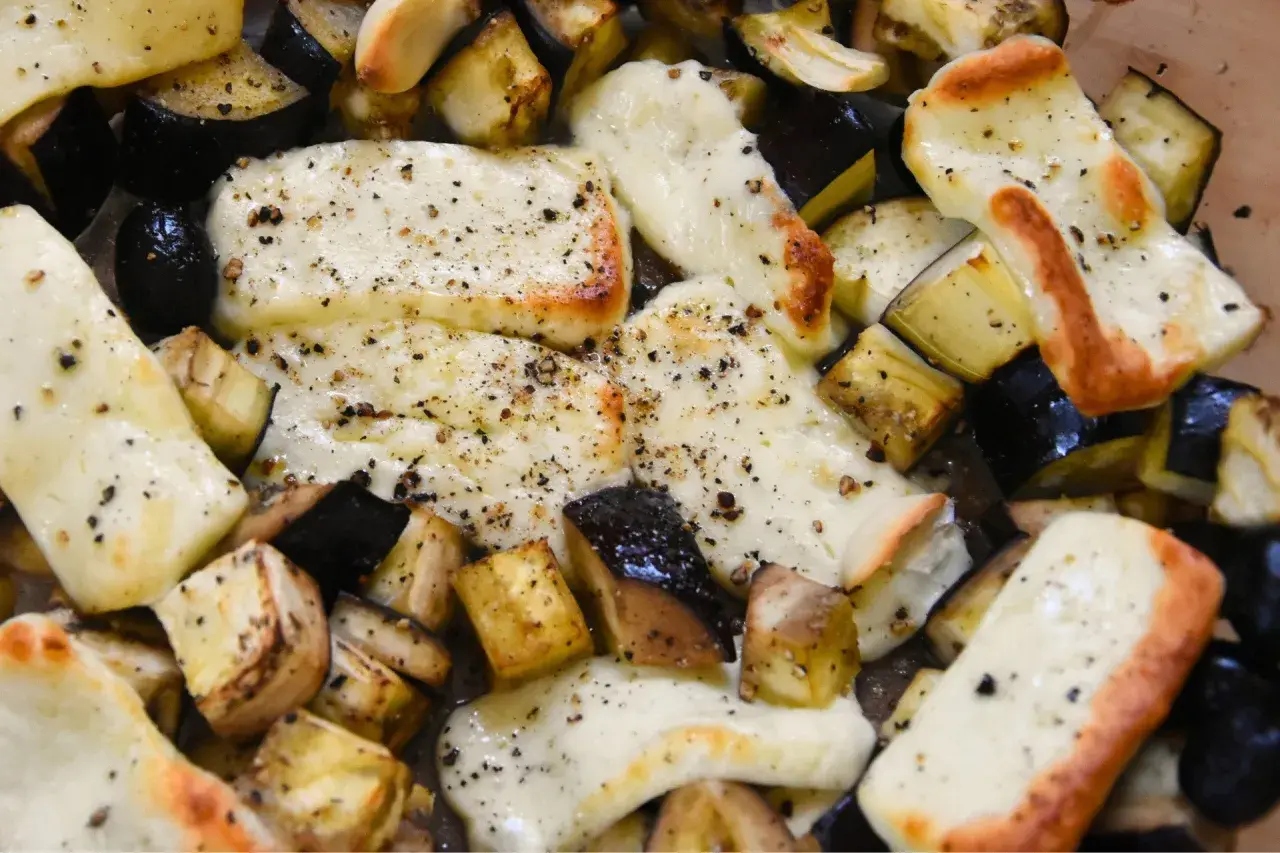 Pyszne halloumi z piekarnika, zapieczone z kawałkami bakłażana, posypane świeżo mielonym pieprzem. Idealne danie.