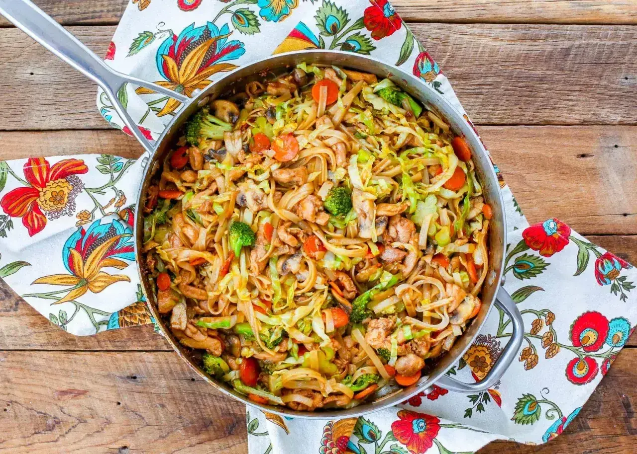 Smażony makaron z kurczakiem i warzywami: brokuły, marchewka, kapusta i pieczarki w sosie. Pyszne danie w woku.