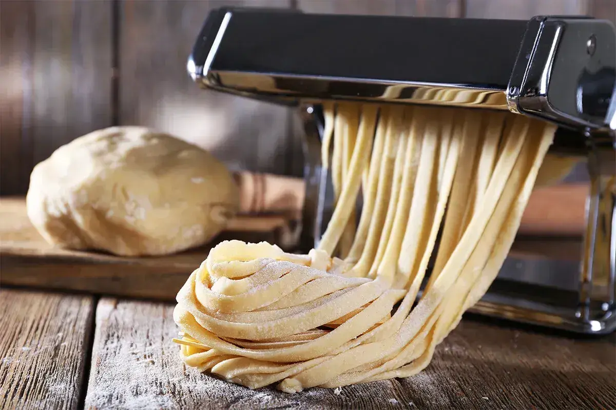 Maszyna do makaronu tworzy świeże tagliatelle z ciasta. Idealny sposób, jak zrobić makaron w domu.