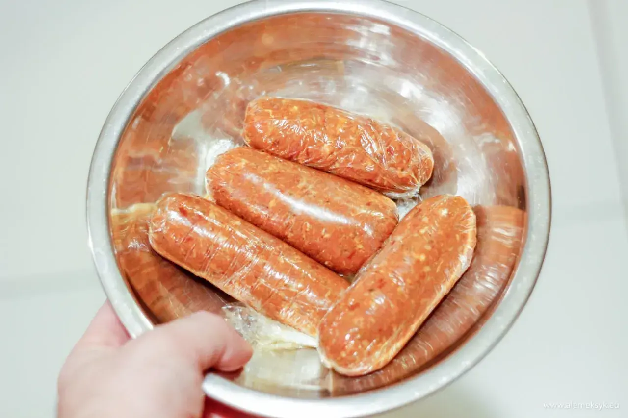 Cztery surowe kiełbaski chorizo w folii spożywczej, gotowe do przygotowania pysznego dania.