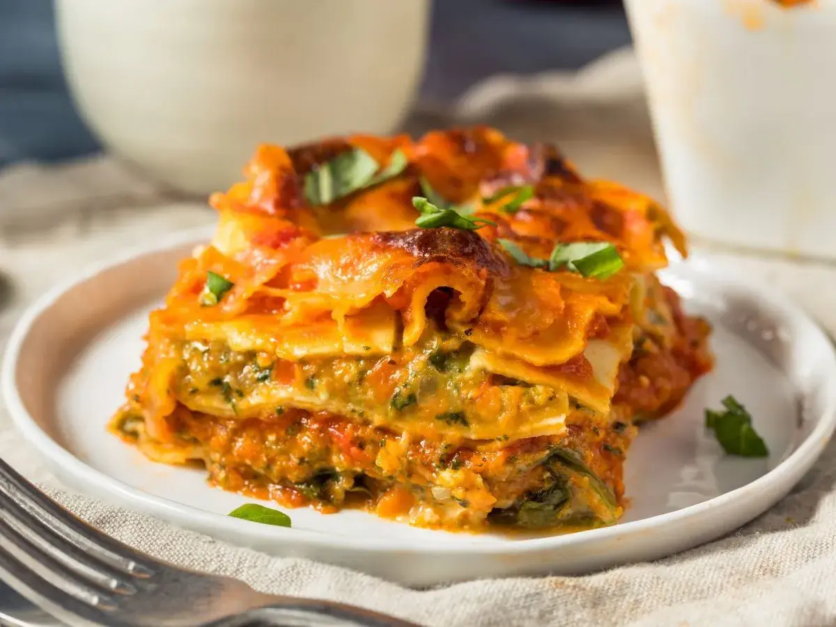 Pyszna lasagne wegetariańska z warzywami i sosem pomidorowym, udekorowana świeżą bazylią.