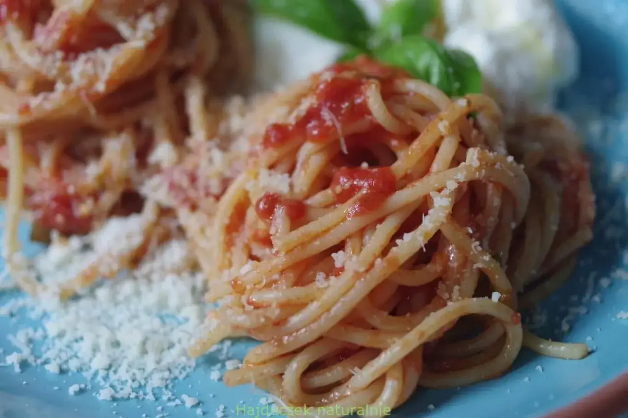 Pyszne spaghetti ze świeżych pomidorów, posypane parmezanem, z listkami bazylii. Idealne na letni obiad.
