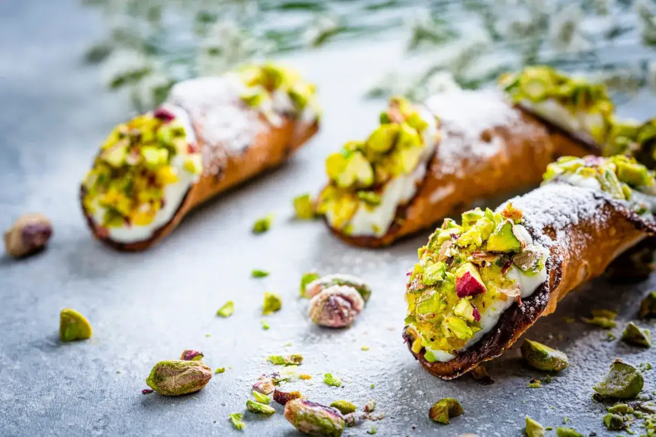Pyszne cannoli pistacjowe posypane cukrem pudrem i orzechami. Idealna przekąska dla łasuch&oacute;w.