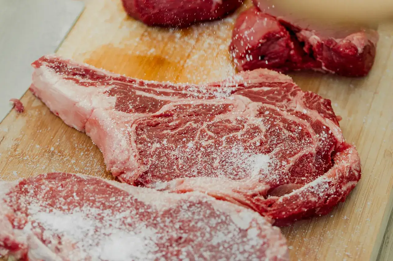 Surowa wołowina na desce, posypana solą. Idealna do smażenia na patelni lub grillu.