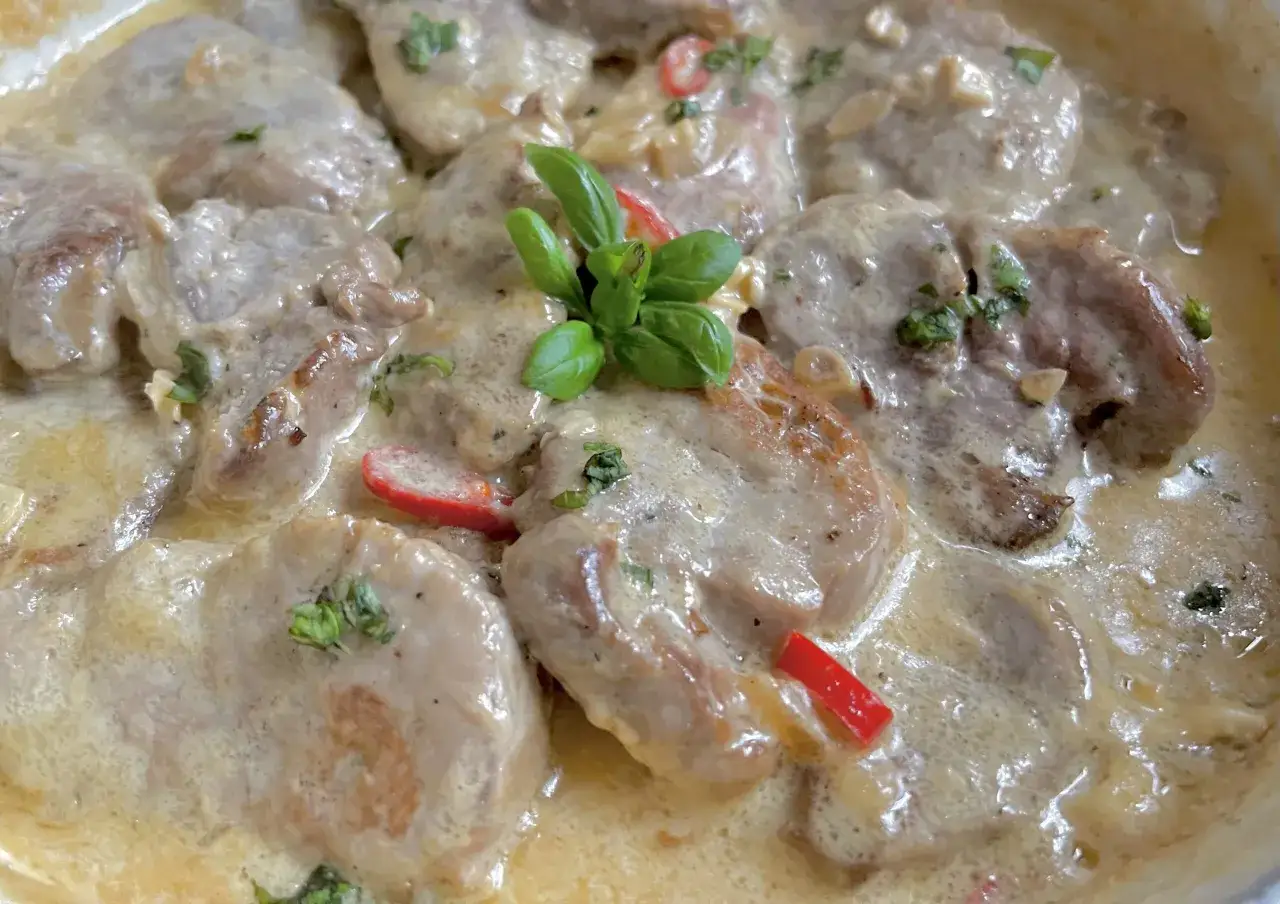 Soczyste polędwiczki w kremowym sosie camembert, udekorowane listkami bazylii i kawałkami papryki.