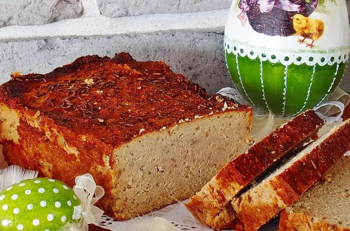Pyszny, domowy pasztet z przyprawami, pokrojony na kromki, obok wielkanocne jajka.