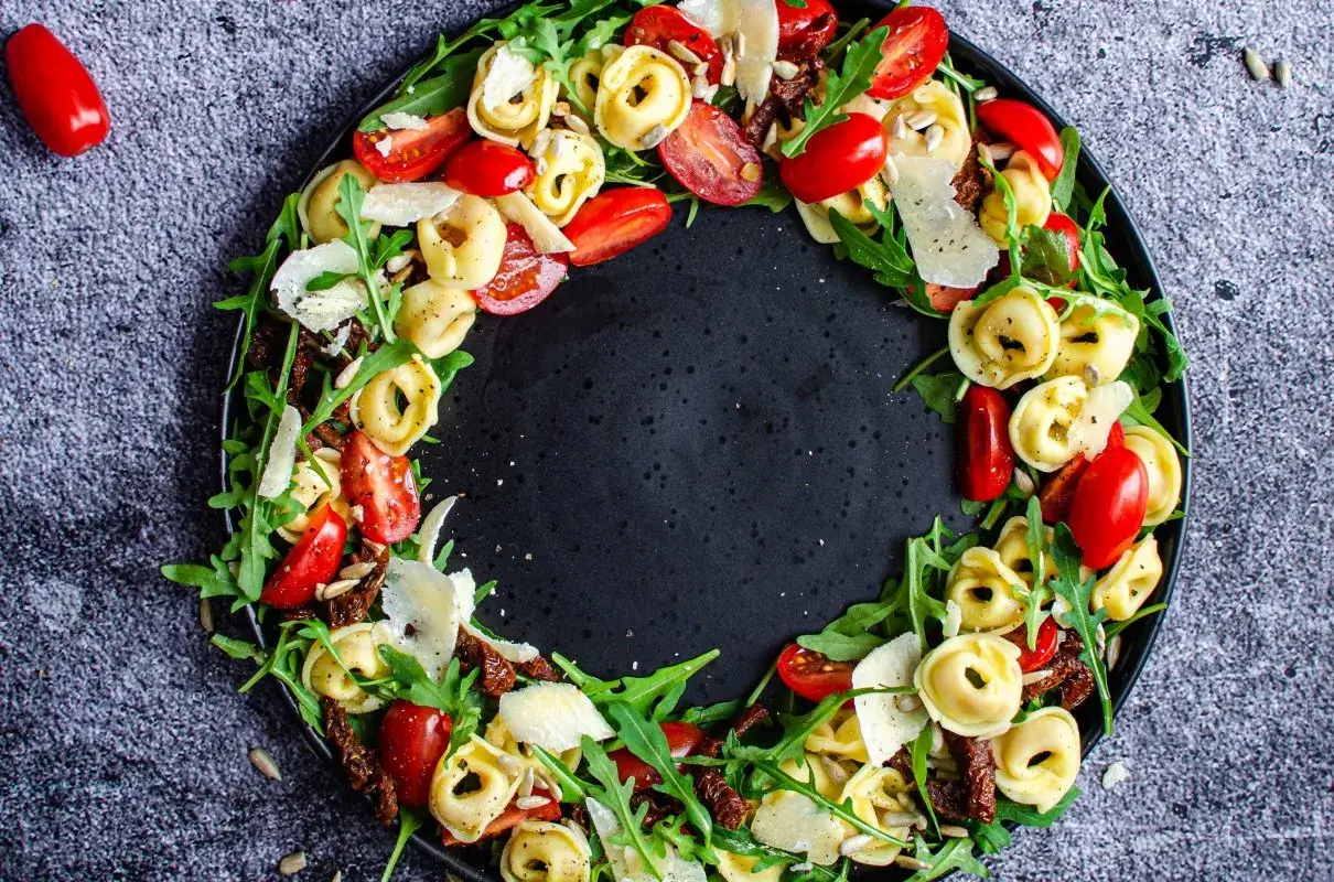 Kolorowa sałatka z tortellini, pomidorkami koktajlowymi, rukolą, płatkami parmezanu i suszonymi pomidorami.