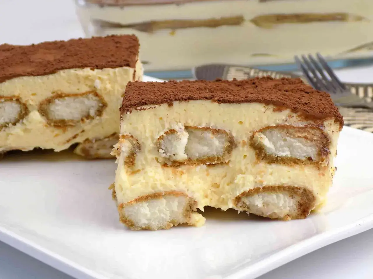 Pyszne tiramisu przepis na talerzu. Warstwy biszkoptów i kremu, posypane kakao.