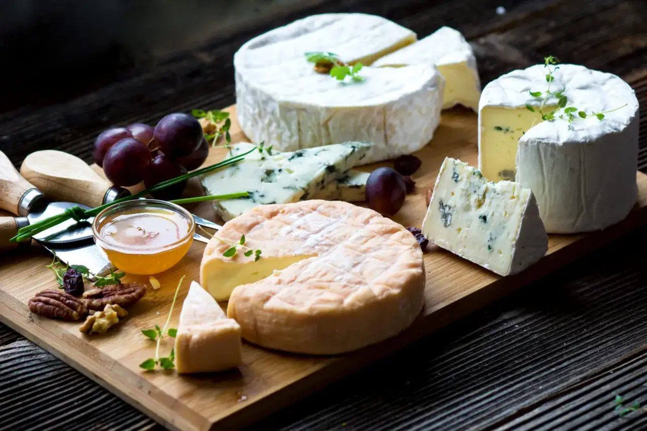 Deska serów z mleka krowiego: pleśniowy, camembert, brie. Winogrona, miód i orzechy dopełniają kompozycję.