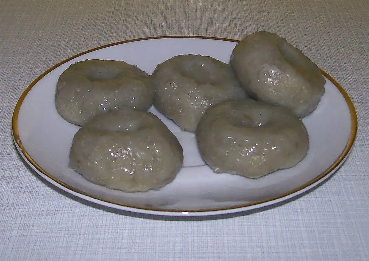 Szare kluski, przepis babci. Domowe, okrągłe kluski z dziurką, podane na białym talerzyku.