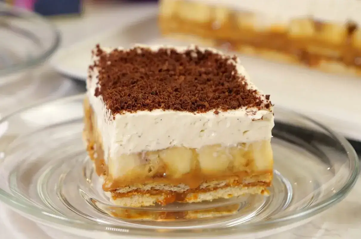 Pyszny kawałek banoffee z warstwami banana, karmelu i bitej śmietany, posypany czekoladą. Idealny deser.
