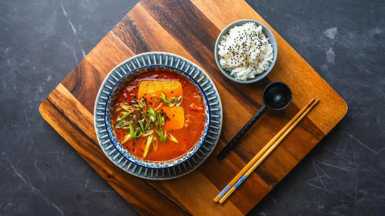 Aksamitna zupa koreańska z tofu i szczypiorkiem, podana z ryżem i pałeczkami.