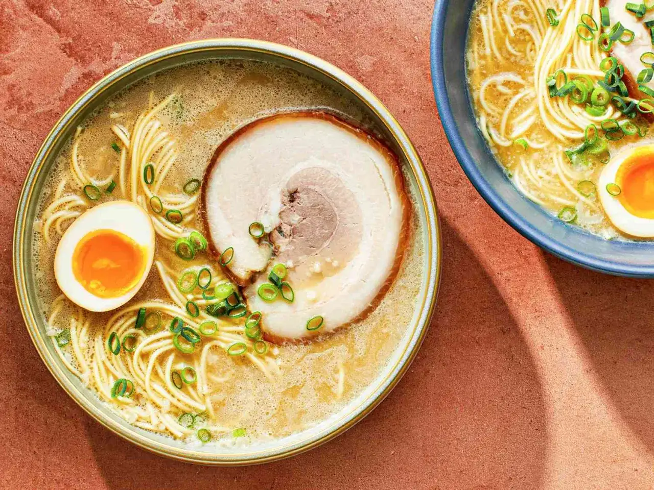 Dwie miski aromatycznych zup japońskich: ramen z plastrem chashu, połówką jajka i szczypiorkiem.