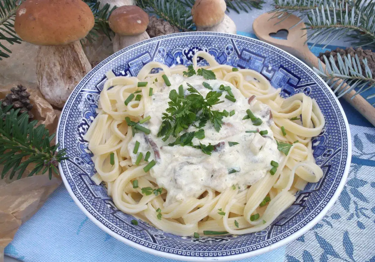 Makaron wstążki w kremowym sosie grzybowym, ozdobiony natką pietruszki i szczypiorkiem. Idealny na jesienne przepisy.