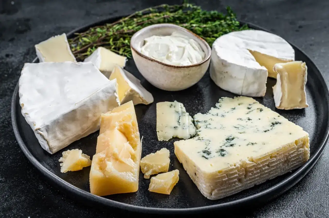 Różne rodzaje sera pleśniowego: brie, ser z niebieską pleśnią, parmezan i serek śmietankowy.