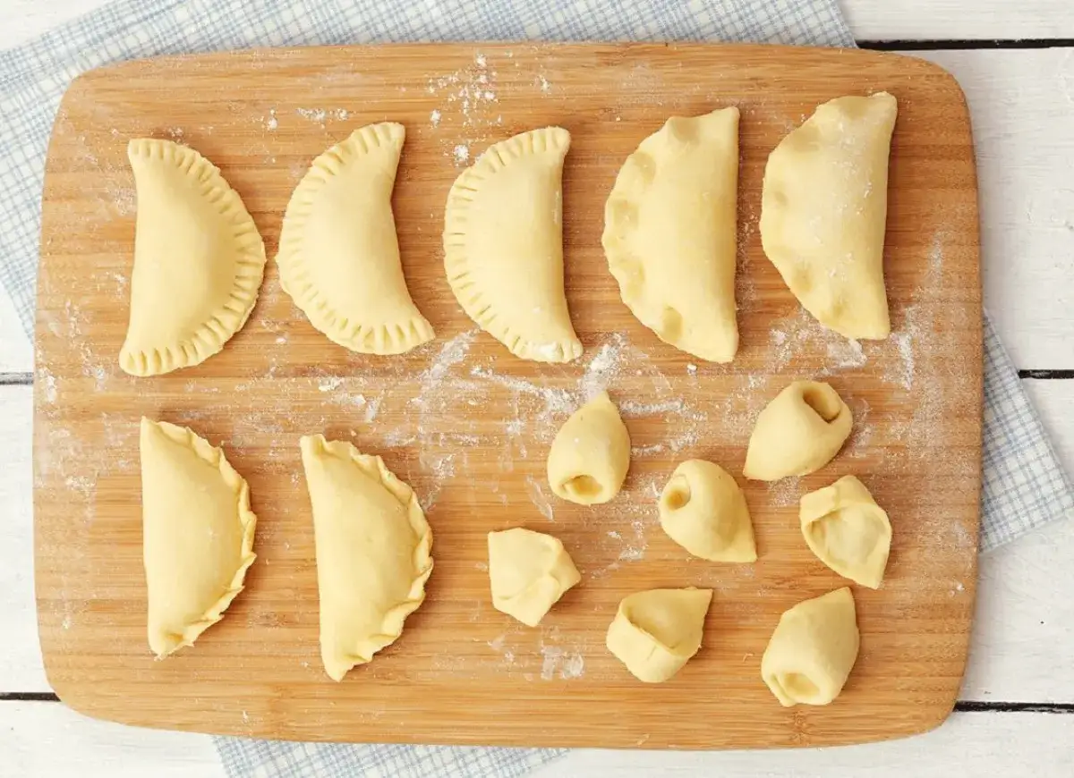 Surowe pierogi i uszka na desce. Czy pierogi trzeba od razu gotować? Niekoniecznie, można je zamrozić.