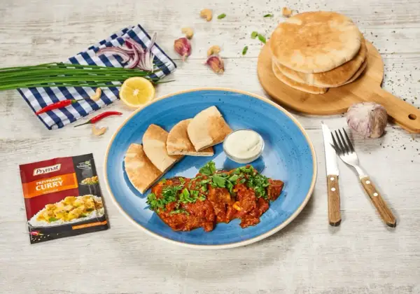 Pyszne wołowina po indyjsku z pitą i dipem. Obok przyprawa curry, czosnek, cytryna i chili.