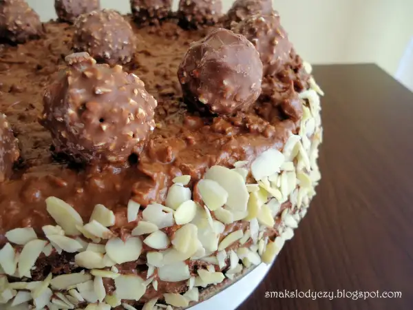 Pyszny tort Ferrero Rocher, obficie udekorowany czekoladowymi kulkami i płatkami migdałów.