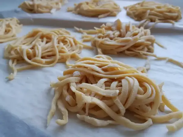 Świeże, domowe tagliatelle uformowane w gniazda. Zastanawiasz się, ile jajek do makaronu? Te wyglądają na idealne!