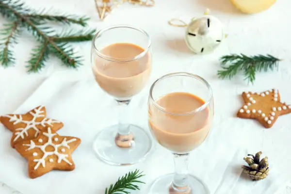 Dwa kieliszki z kremowym likierem nutella, ozdobione świątecznymi pierniczkami i gałązkami świerku.